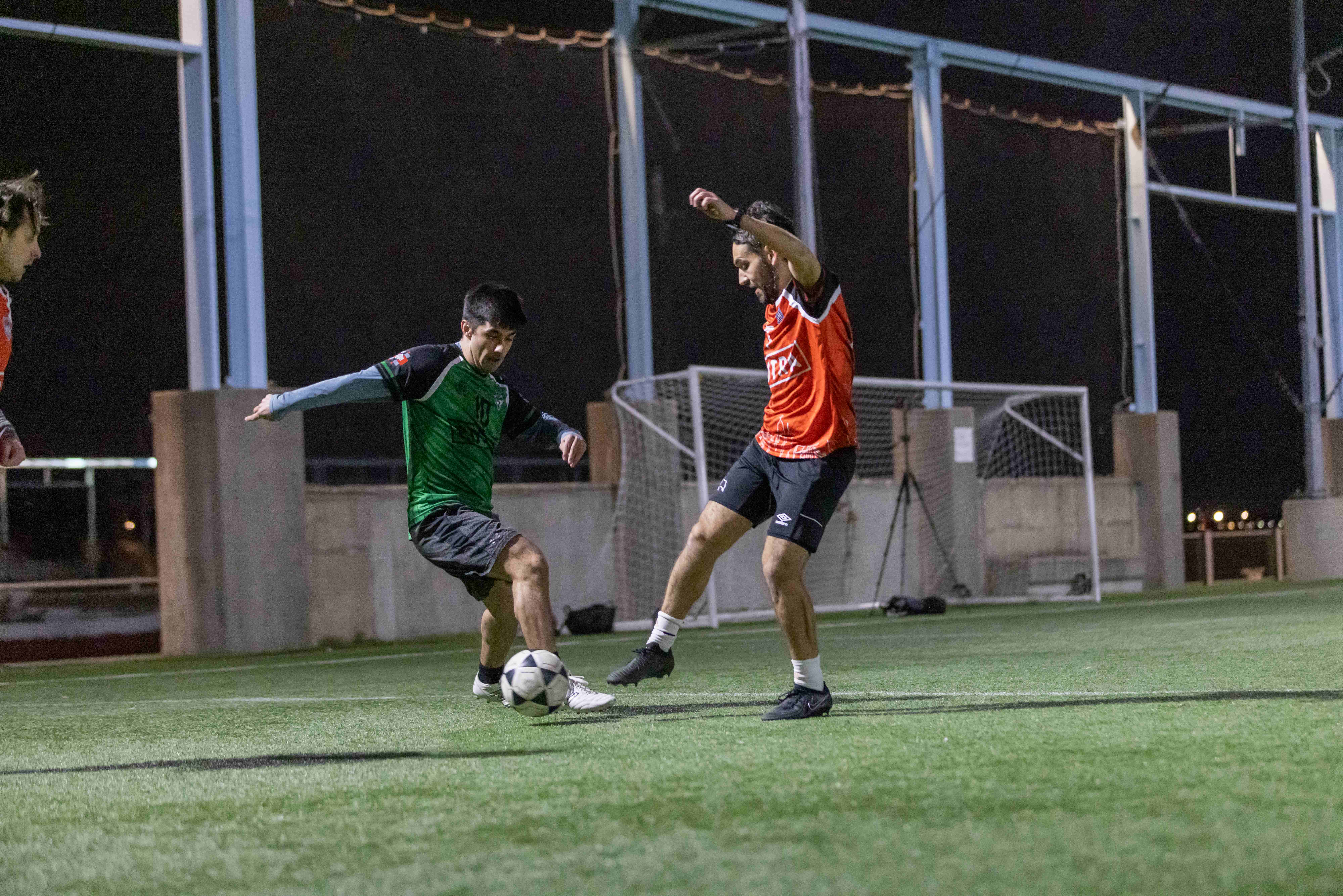 Players competing during night pickup soccer game