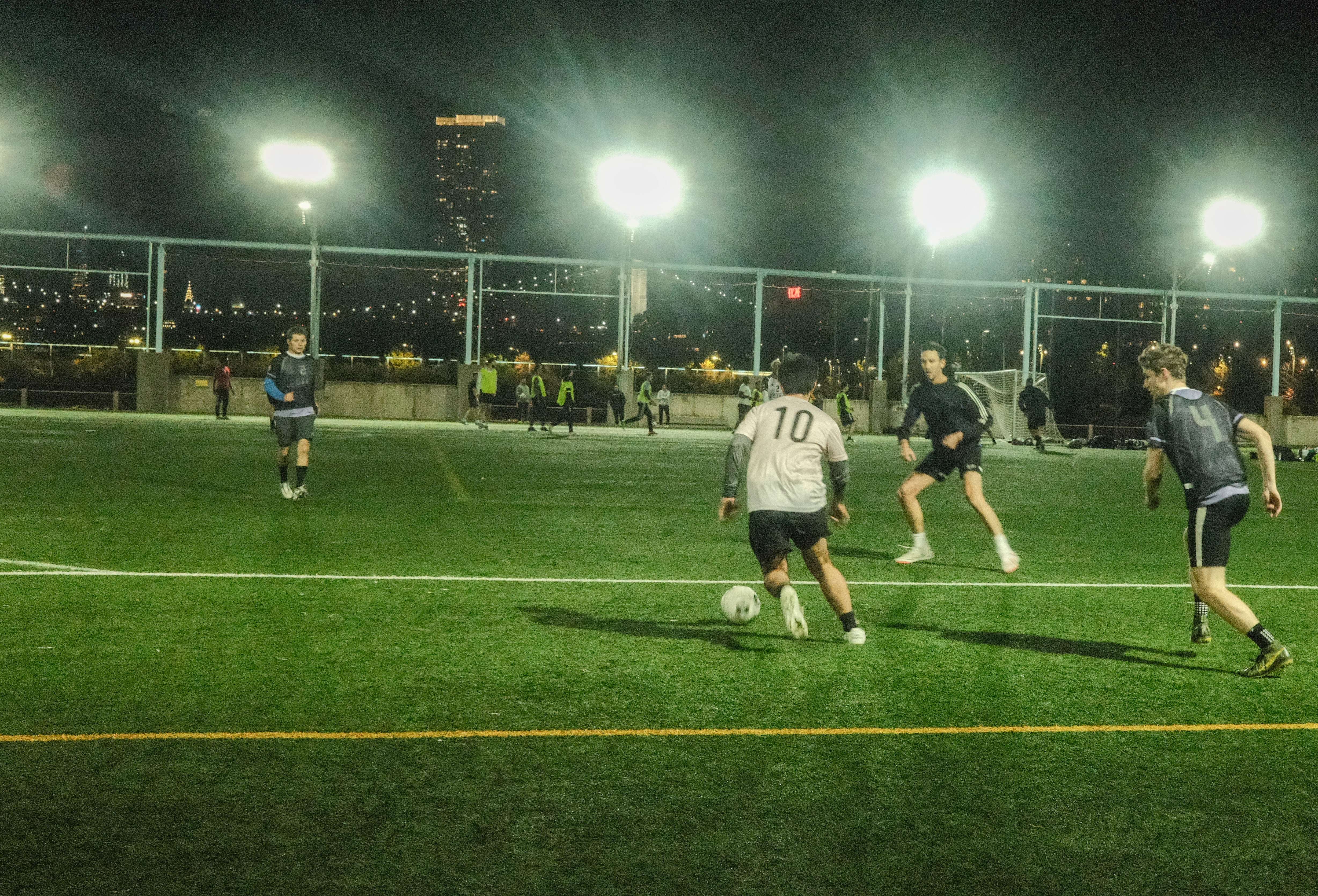 Pickup soccer game at night with multiple players on field