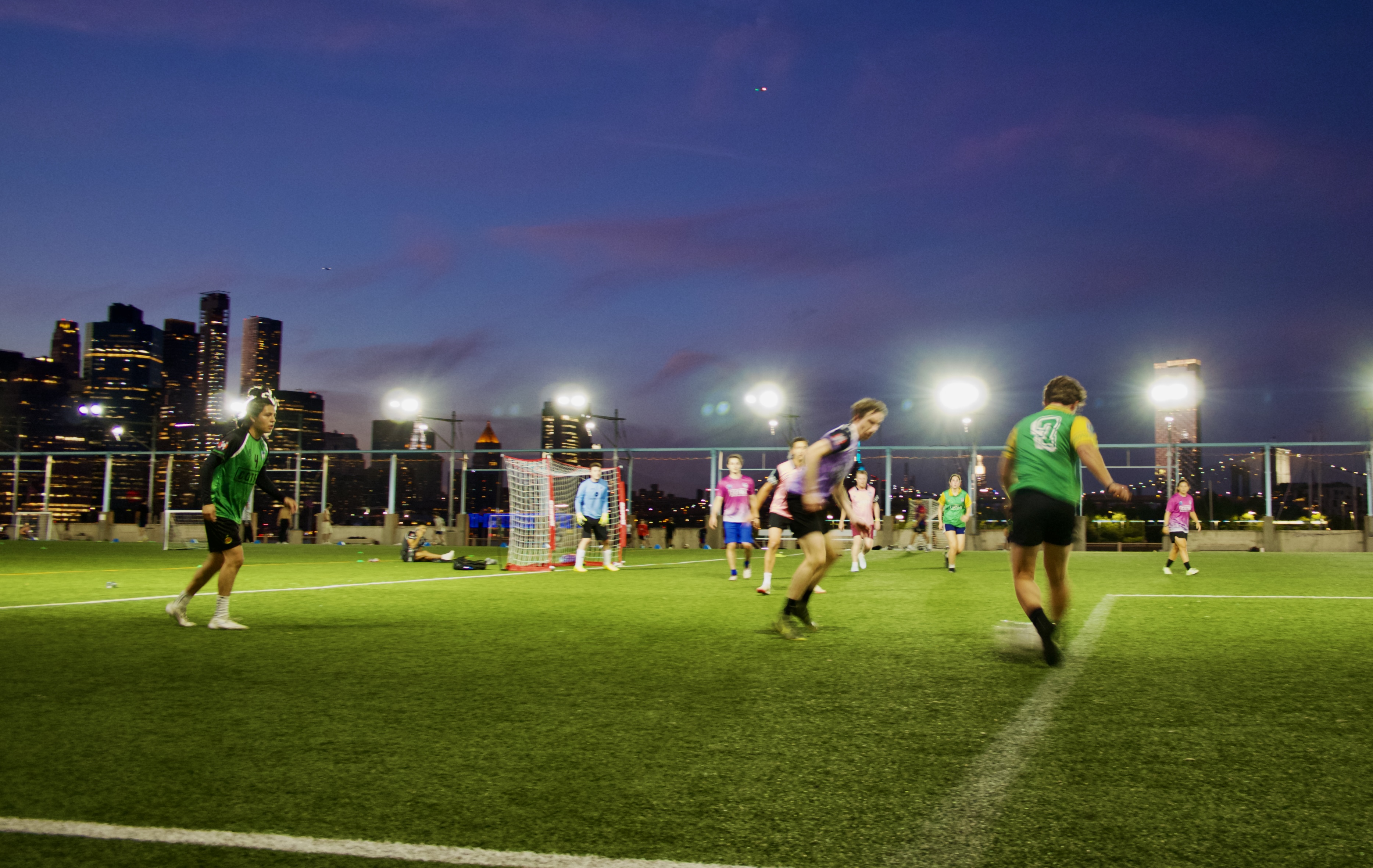 Night pickup soccer game at Brooklyn Bridge Park with Manhattan skyline